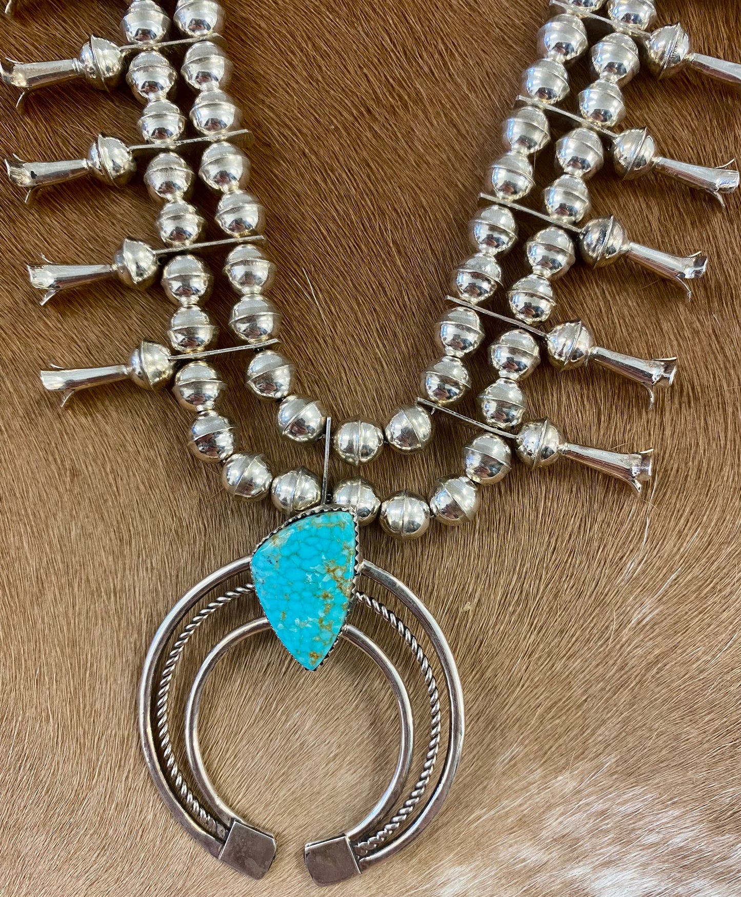 Gorgeous sterling silver handmade Turquoise Squash Blossom necklace stamped STERLING and signed with the initials “PG” on the back of the naja by the artist. A photo of the hallmark will be in the photos above. This necklace will make for a stunning addition to anyone’s jewelry collection. A statement piece for any outfit! The perfect amount of silver and turquoise is handcrafted into this unique piece.