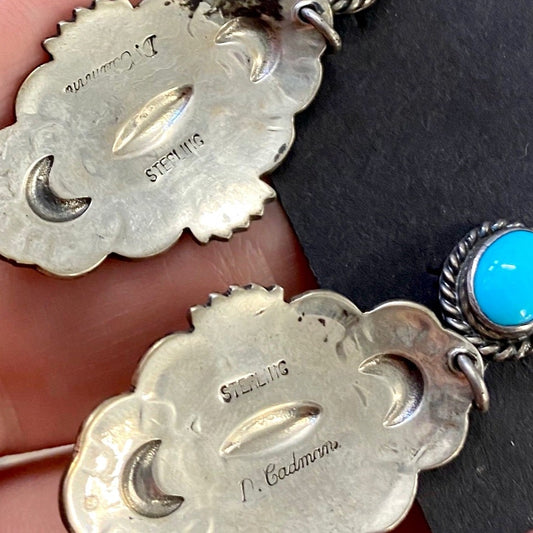 The D. Cadman Turquoise Earrings - Ny Texas Style Boutique Turquoise post sterling silver dangle statement earrings, signed and made by Native American artist silversmith Darrell Cadman. These beauties are Native made stamped sterling and signed "D. Cadman" on the back. Size: 1.75” Inches length Stone: Turquoise Signed: YES "D. Cadman" Artist/Hallmark: Darrell Cadman