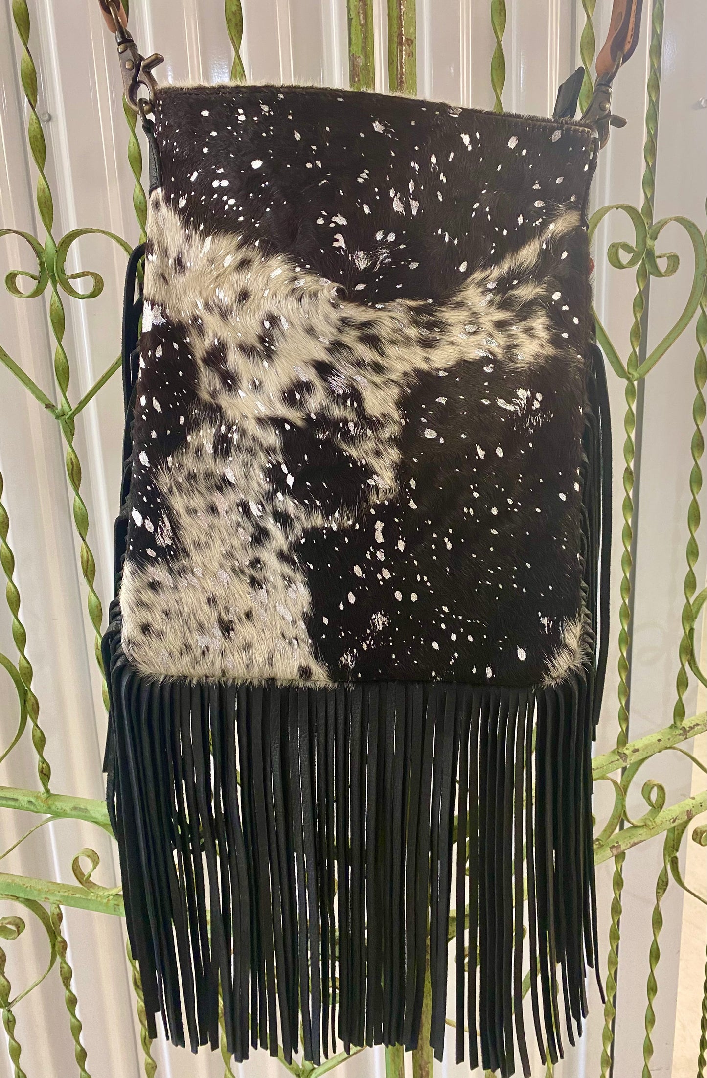 Large Black and White American Darling Western Crossbody Fringe Purse If you like cowhide and fringe and you're looking for a really cute crossbody purse that is also concealed carry, we've got just the purse for you! The Alex crossbody fringe purse is accented with silver metallic spots across the black and white hair on hide cowhide. It also has a removable tooled leather shoulder strap. It features 2 open pockets and 1 zipped pocket inside.
