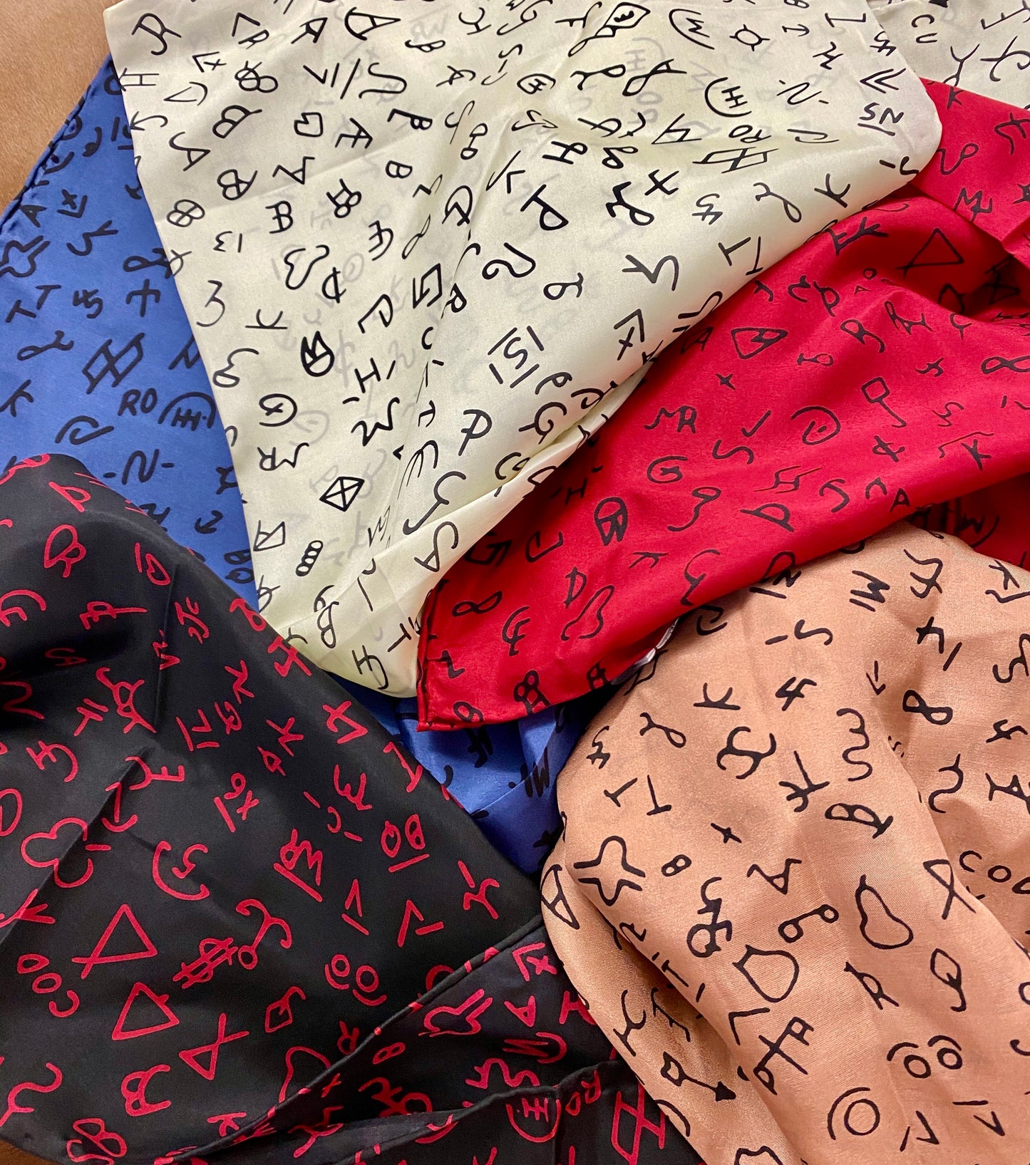 The Red Brand Wild Rag - Ny Texas Style Boutique Black Brands on red background cowboy scarf Wild Rag with hand stitched hem. Perfect for her or him. This can be worn around your neck, in your hair, pocket square, and so many other styles. Gorgeous Silk wild rag featuring various cattle/livestock brands. Also available in a variety of colors on our website. Fabric: 100% Silk Size: 20” X 20” - 20" Square Colors: Red, Black Care Instructions: Hand Wash or Dry Clean - Hang Dry