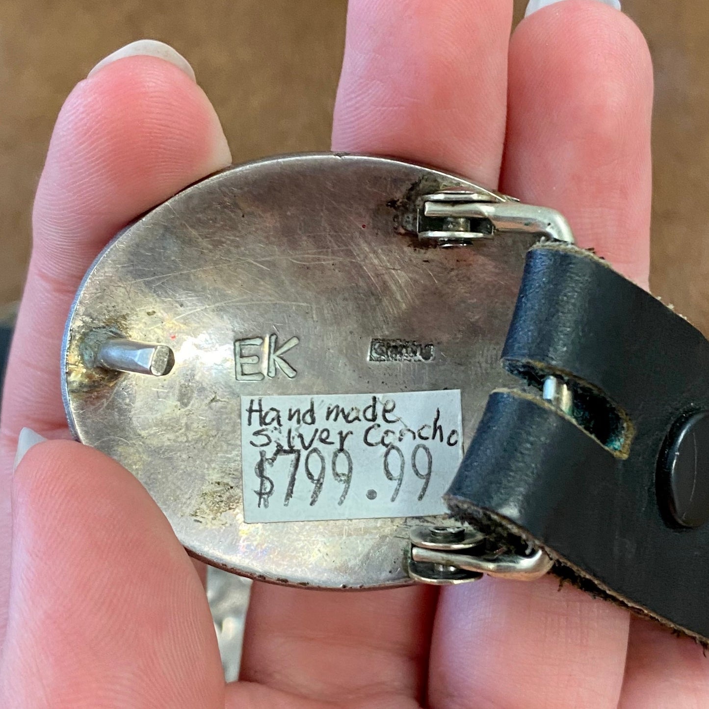 Old pawn silver piece showcases ten Conchos and one buckle Concho each having an etched traditional geometric Navajo design. The piece is from the mid to early 20th century. It features a black leather belt with movable Concho sterling silver pieces. It's  signed, "EK" and stamped STERLING".  The Conchos are made with a heavy sterling silver construction. Each Concho is 1.5"x1 7/8".  Belt is 37.5" length.