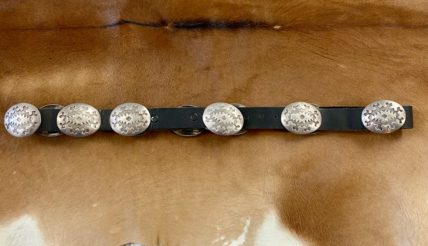 Old pawn silver piece showcases ten Conchos and one buckle Concho each having an etched traditional geometric Navajo design. The piece is from the mid to early 20th century. It features a black leather belt with movable Concho sterling silver pieces. It's  signed, "EK" and stamped STERLING".  The Conchos are made with a heavy sterling silver construction. Each Concho is 1.5"x1 7/8".  Belt is 37.5" length.