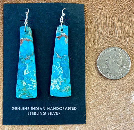 Gorgeous unique large turquoise slab sterling silver Native American made earrings. Beautiful statement handmade earrings, perfect for so many different occasions. From weddings, NFR, to everyday wear! Size: 2” inch length Stone: Turquoise Native American Made Sterling Silver Large Turquoise Slab Earrings