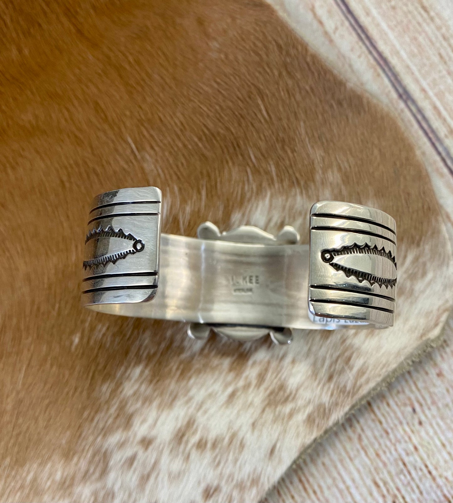An absolutely stunning large single blue lapis stone with stamped silver detailing down the sides sterling silver cuff bracelet. This is a amazing statement piece that you are sure to receive compliments on! A piece that can be cherished and passed down generations for your children and grandchildren to admire for decades as well as lifetimes to come. Made by the talented Native American artist and silversmith Irene Kee. This beauty is stamped STERLING and signed "I. KEE" inside of the cuff bracelet.