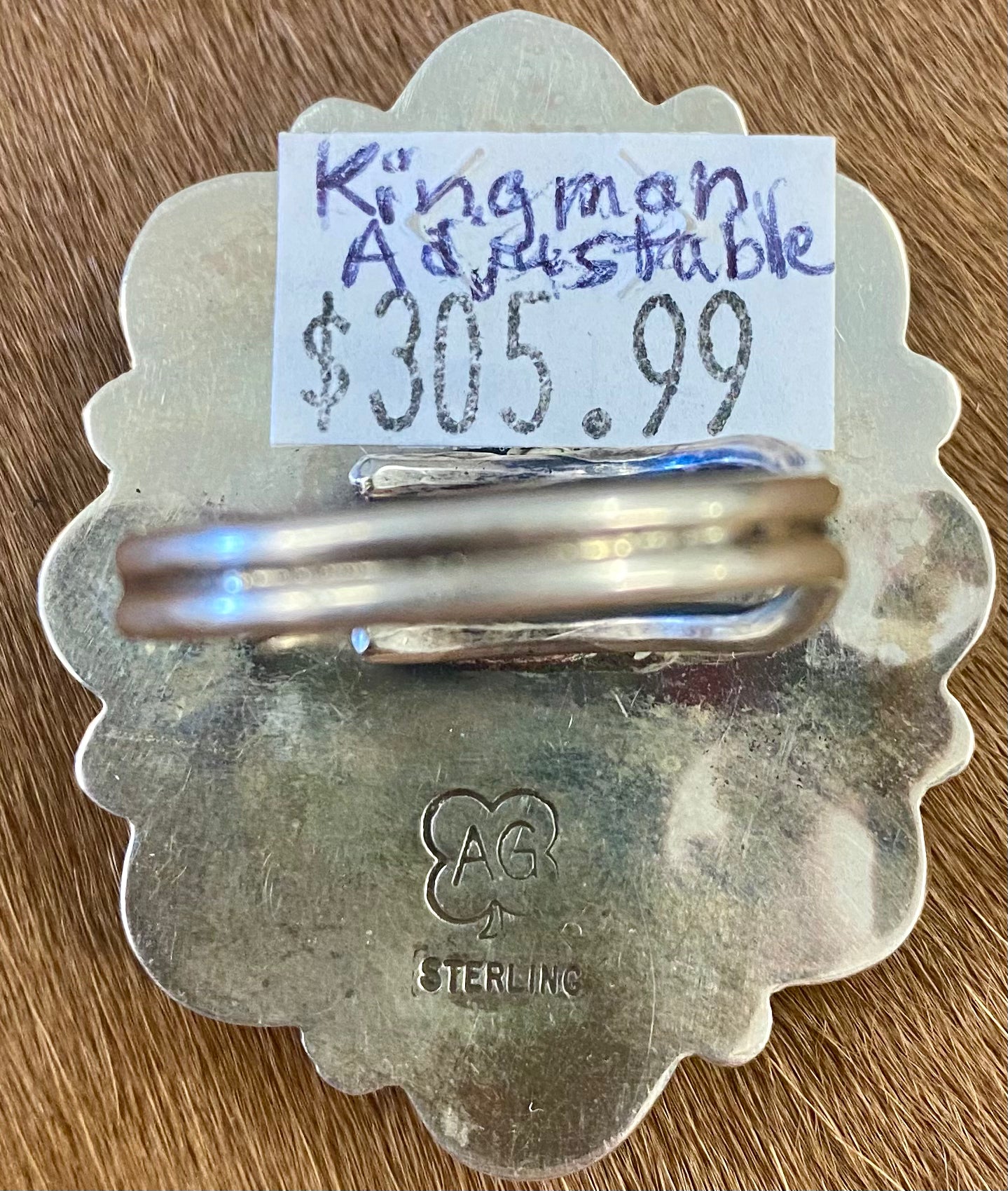 Gorgeous adjustable Kingman turquoise large cluster sterling silver ring. Nine unique turquoise stones grouped together. Stamped sterling and signed "AG" inside of a clover by Native American artist silversmith duo Arnold & Carleena Goodluck. Beautiful native made piece of art to add to your jewelry collection! Size: 1.5” inch length Signed: YES "AG" Hallmark/Artist: Arnold & Carleena Goodluck Stone: Kingman Turquoise