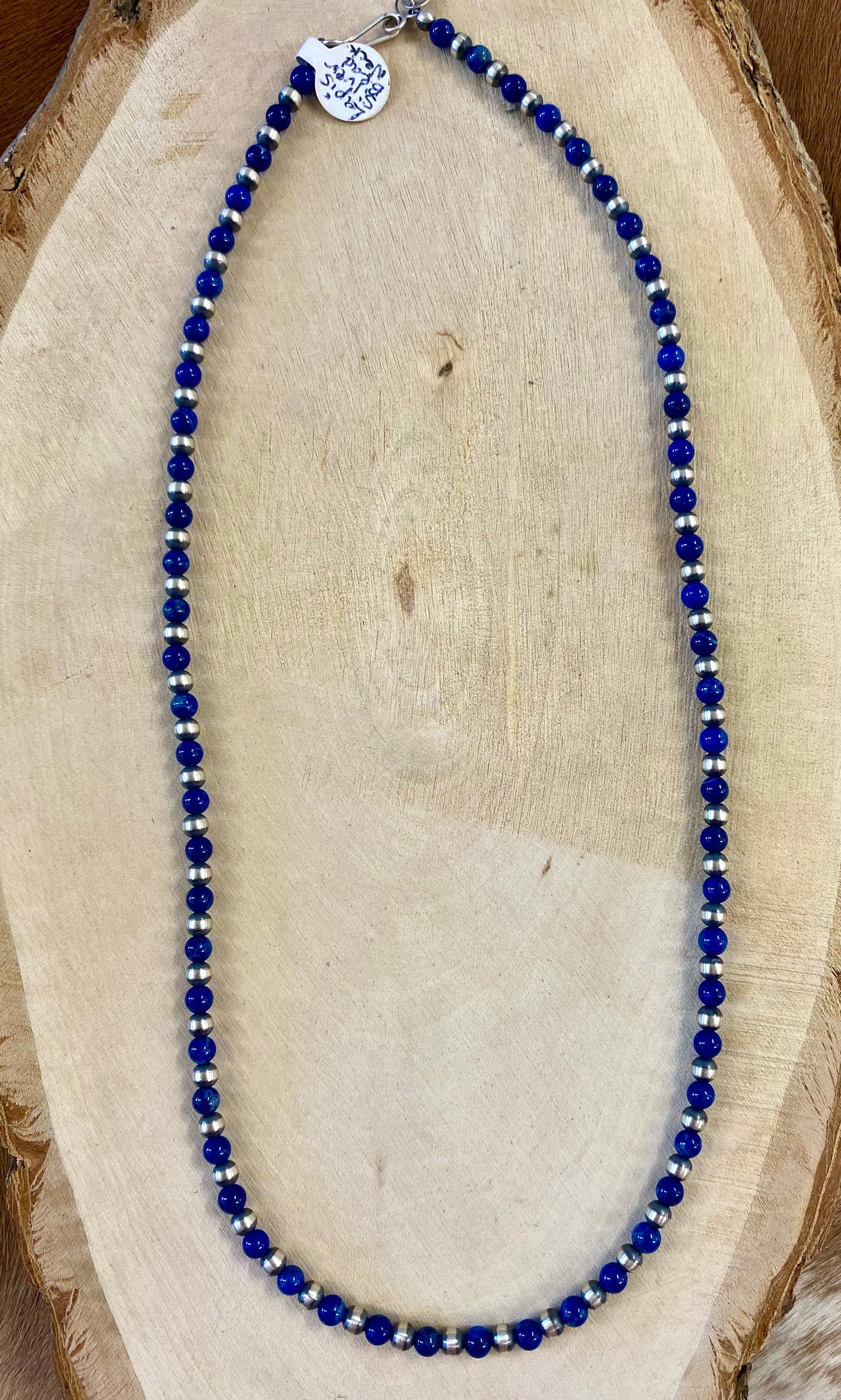 Sterling silver single strand Native American made hand strung Lapis and Navajo Pearl 20” inch length necklace. The perfect necklace to wear alone, layered with other necklaces, or with a pendant! This necklace is stamped .925 on a small pendant on the hook clasp. Size: 20" Inches Length Stone: Lapis and Navajo Pearl Signed: YES ".925"