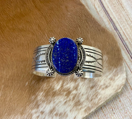 An absolutely stunning large single blue lapis stone with stamped silver detailing down the sides sterling silver cuff bracelet. This is a amazing statement piece that you are sure to receive compliments on! A piece that can be cherished and passed down generations for your children and grandchildren to admire for decades as well as lifetimes to come. Made by the talented Native American artist and silversmith Irene Kee. This beauty is stamped STERLING and signed "I. KEE" inside of the cuff bracelet. 