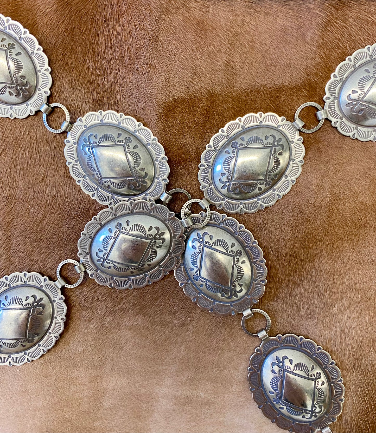 Beautiful 15 piece concho Nickle silver belt. This belt is adjustable as you can latch it on to any of the round pieces in-between the concho pieces. Each concho piece has a design etched on to it. This belt is amazing and will go so well with any outfit. Everyone needs a concho belt in their accessory wardrobe. Size: 42” inches 15 Concho pieces each 1.75” x 2” inches