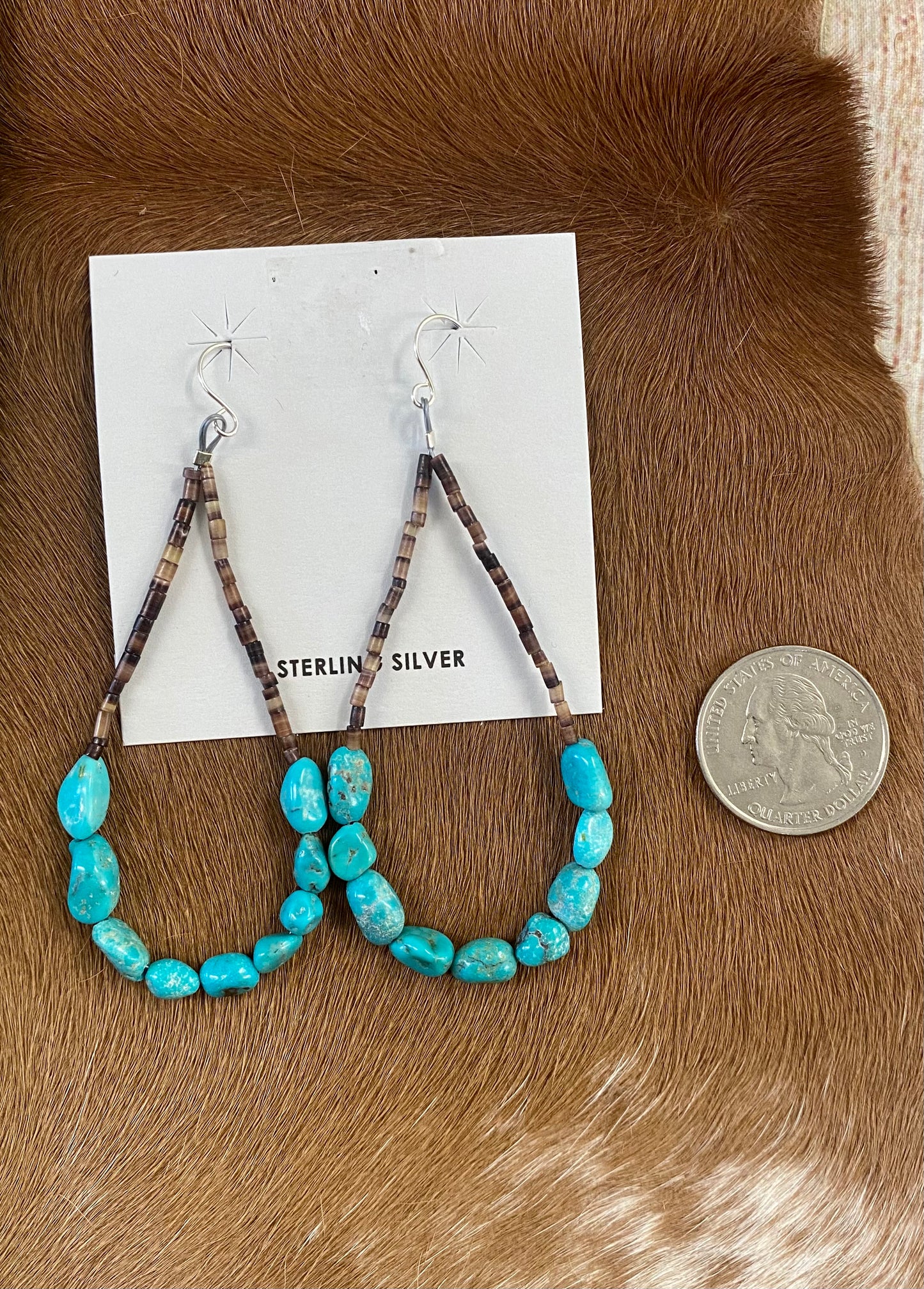 Beautiful Heshie Native American-made teardrop drop hook earrings with turquoise. The ideal jewelry item to give as a present or to keep for yourself! These are light and straightforward while still being elegant. The perfect turquoise teardrop earrings for anyone's jewelry collection! Size: 3” inch length Stone: Turquoise