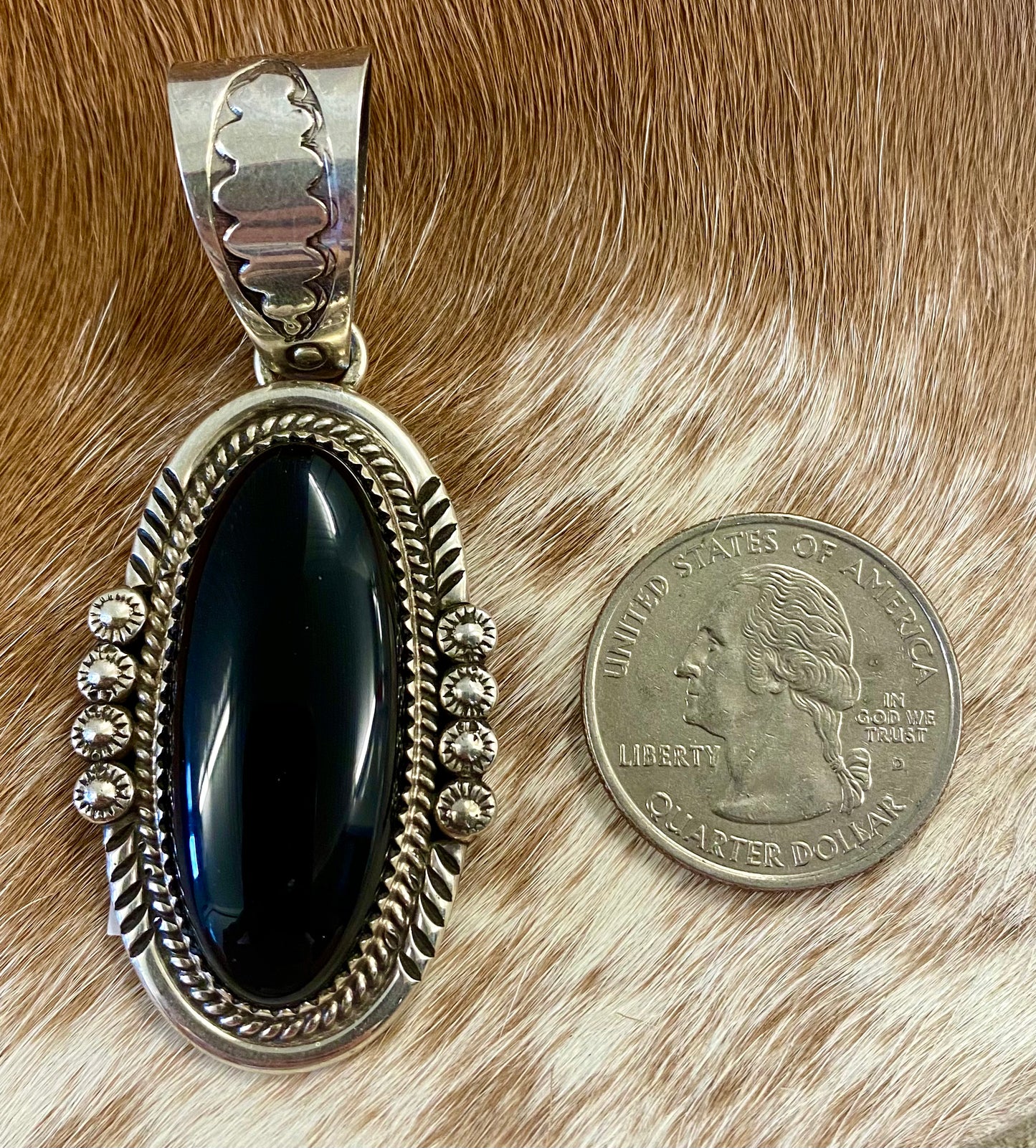 The perfect single stone sterling silver Native American made onyx pendant to add to any necklace. This piece will look especially gorgeous on a strand of Navajo pearls. Stamped sterling and signed PY by Native artist silversmith Phillip Yazzie. Size: 2” inches length without bale x 1” inch width - 1” inch bale Signed: YES "PY" Hallmark/Artist: Phillip Yazzie Stone: Onyx