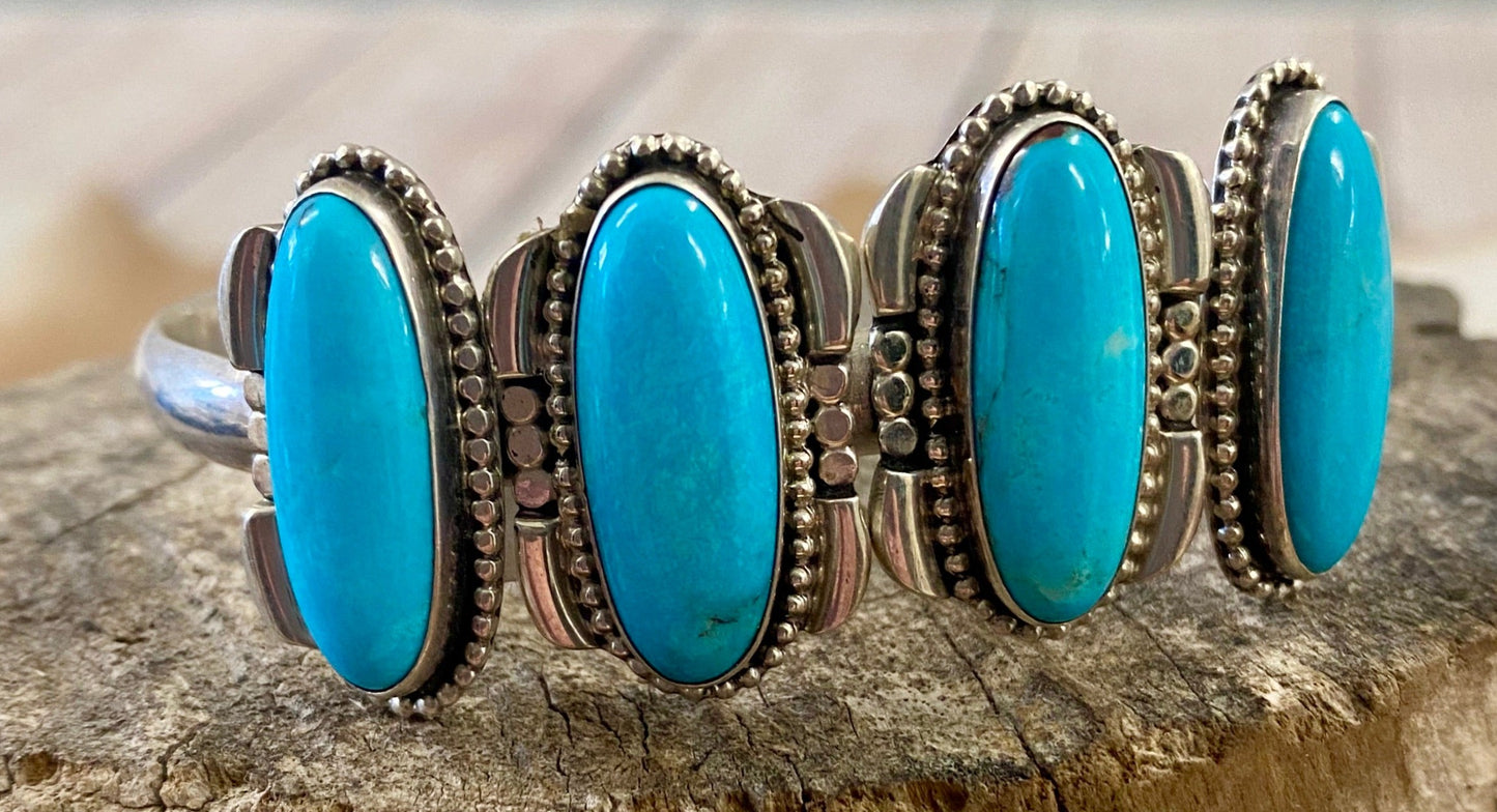 Silver four stone Native American made turquoise stamped sterling and signed cuff. This cuff is absolutely stunning and the perfect piece for your jewelry collection or give as a gift to a loved one. Stamped Sterling & Signed R.B. Inside of a bear icon for Running Bear Shop on the inside of the cuff. Size: Stones are 1” length 6.5” all the way around not including gap Stone: Turquoise Signed: YES "R.B." Inside of a bear icon Hallmark/Artist: Running Bear Shop