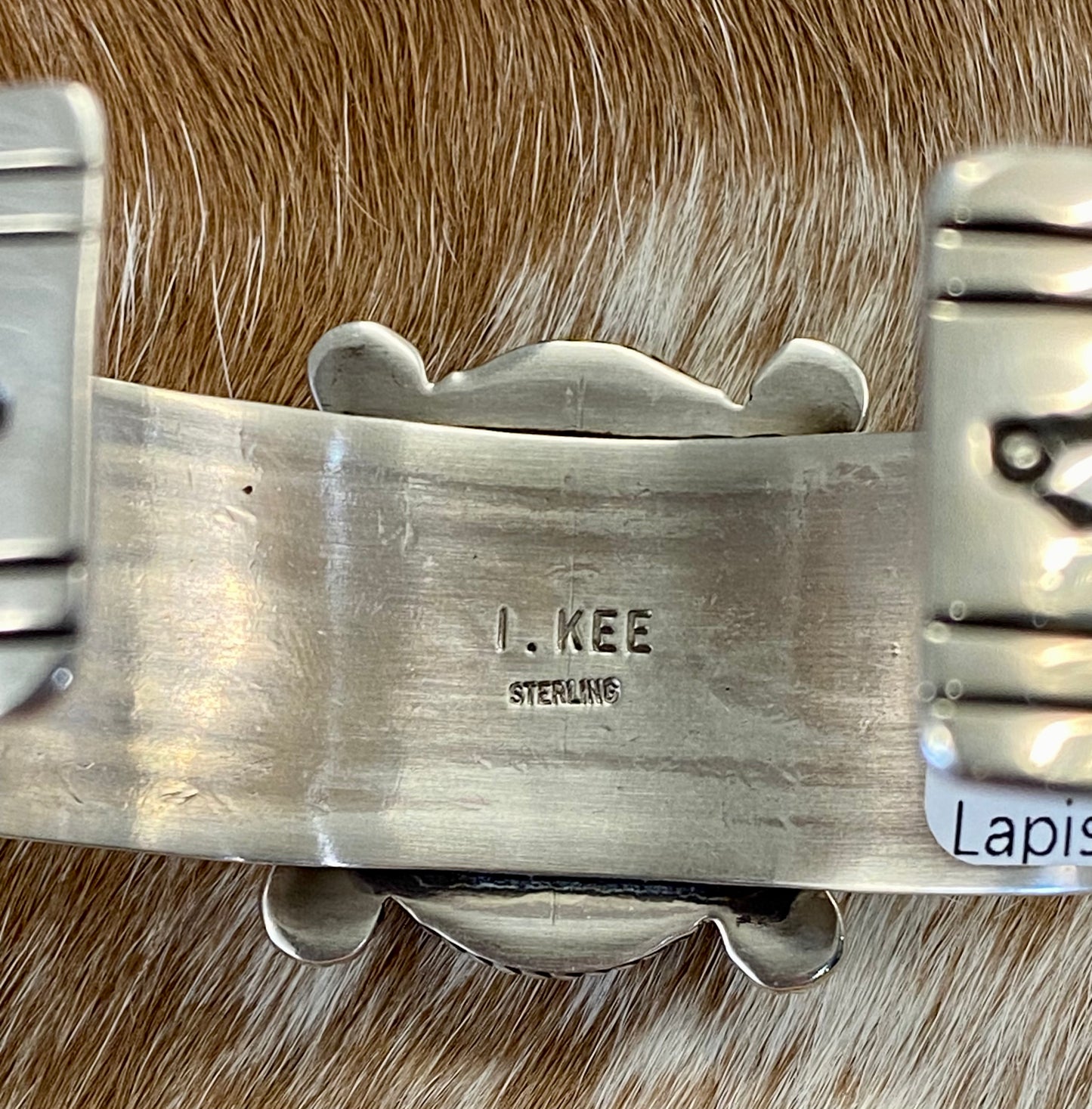 An absolutely stunning large single blue lapis stone with stamped silver detailing down the sides sterling silver cuff bracelet. This is a amazing statement piece that you are sure to receive compliments on! A piece that can be cherished and passed down generations for your children and grandchildren to admire for decades as well as lifetimes to come. Made by the talented Native American artist and silversmith Irene Kee. This beauty is stamped STERLING and signed "I. KEE" inside of the cuff bracelet.