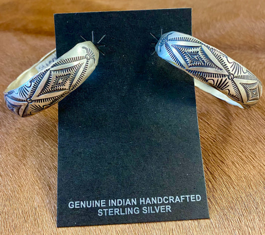 Stunning large statement Native American made sterling silver half hoop post stamped silver earrings. These are sure to make a statement when being worn with any outfit. They are so simple yet elegant. The perfect addition to anyone's jewelry collection! Size: 2” inch length Native American Handmade Stamped Silver Post Half Hoop Unique Earrings