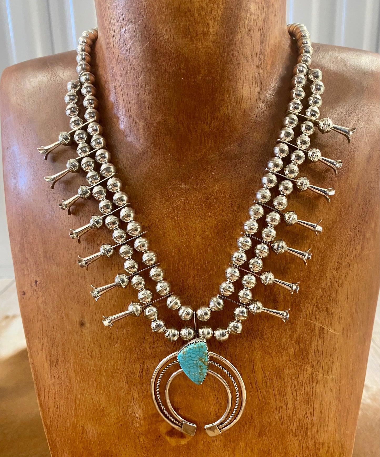 Gorgeous sterling silver handmade Turquoise Squash Blossom necklace stamped STERLING and signed with the initials “PG” on the back of the naja by the artist. A photo of the hallmark will be in the photos above. This necklace will make for a stunning addition to anyone’s jewelry collection. A statement piece for any outfit! The perfect amount of silver and turquoise is handcrafted into this unique piece.