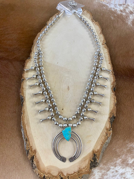 Gorgeous sterling silver handmade Turquoise Squash Blossom necklace stamped STERLING and signed with the initials “PG” on the back of the naja by the artist. A photo of the hallmark will be in the photos above. This necklace will make for a stunning addition to anyone’s jewelry collection. A statement piece for any outfit! The perfect amount of silver and turquoise is handcrafted into this unique piece.