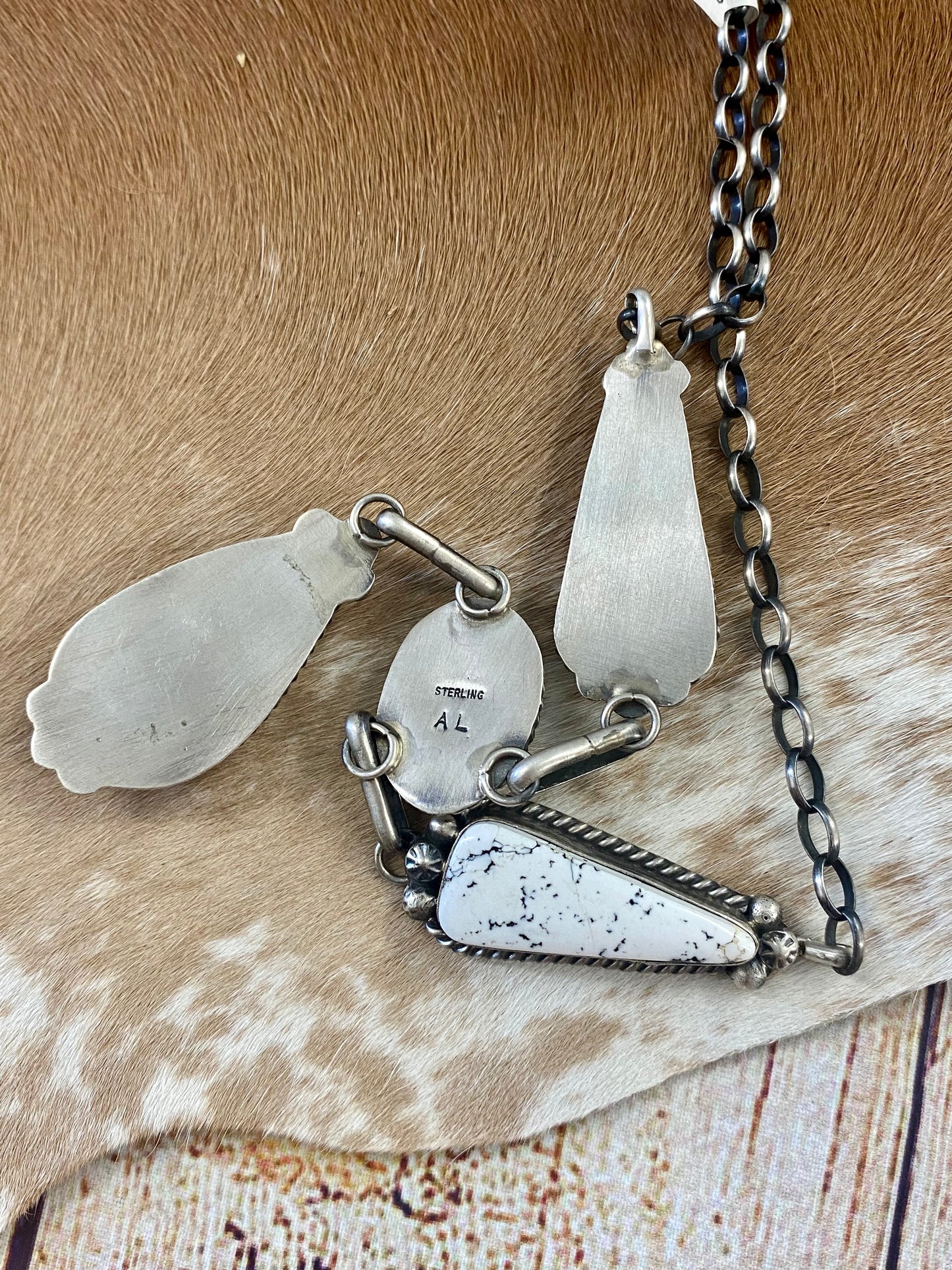Stunning White Buffalo lariat style sterling silver Native American made necklace and drop hook matching White Buffalo sterling silver earrings set. The perfect jewelry set to gift to your loved one or keep for your own jewelry collection! Both pieces are stamped sterling and signed on the back by talented artist silversmith Annie Spencer. Size: 27” inches in length necklace + 1 1/2” inch earrings Stone: White Buffalo Signed: YES "AL" Artist / Hallmark: Annie Spencer