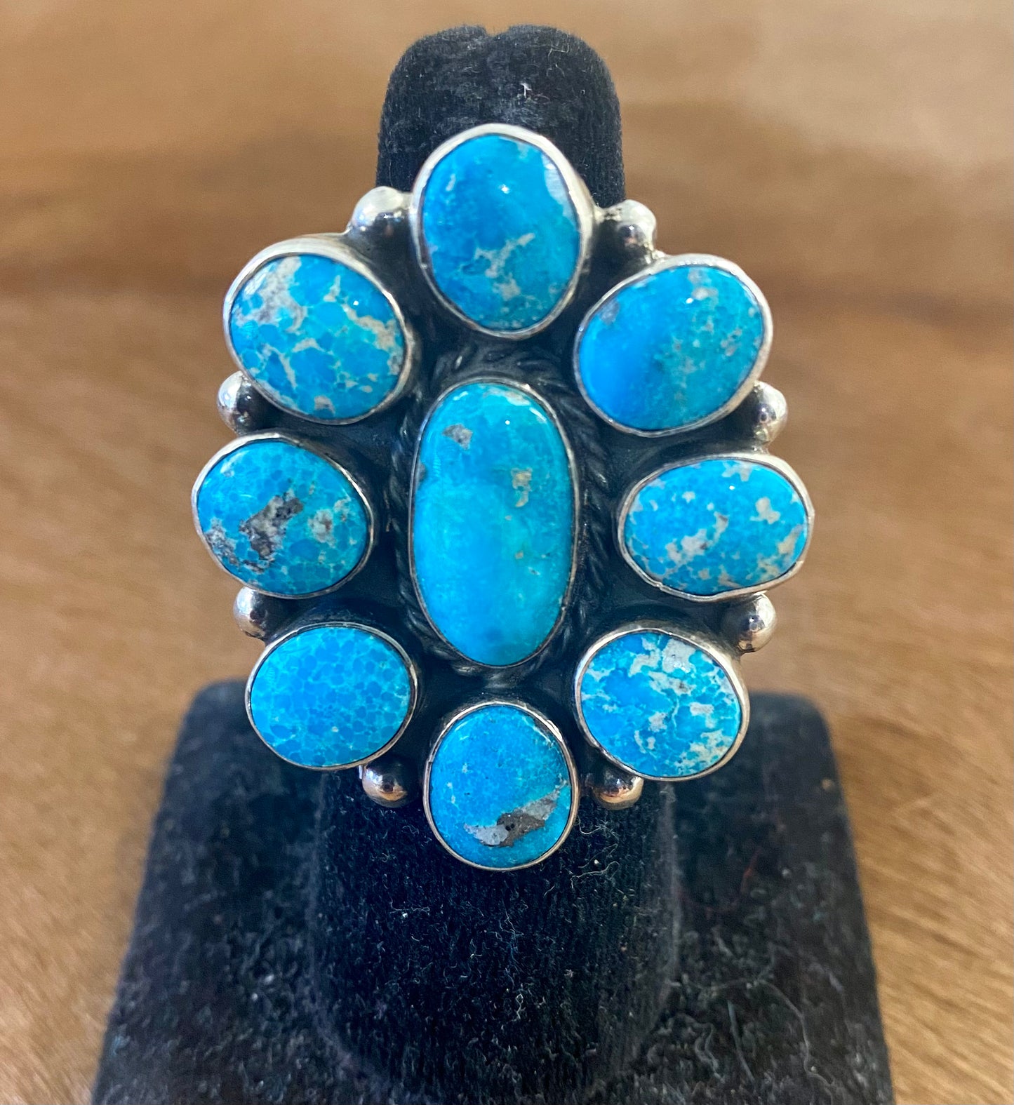Gorgeous adjustable Kingman turquoise large cluster sterling silver ring. Nine unique turquoise stones grouped together. Stamped sterling and signed "AG" inside of a clover by Native American artist silversmith duo Arnold & Carleena Goodluck. Beautiful native made piece of art to add to your jewelry collection! Size: 1.5” inch length Signed: YES "AG" Hallmark/Artist: Arnold & Carleena Goodluck Stone: Kingman Turquoise