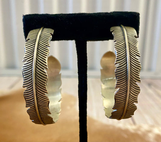 The Feather Indians Silver Earrings Stunning and unique sterling silver large feather post half hoop Native American handmade earrings. Very easy to dress up or down depending on the outfit! Add these beauties to you or your loved ones jewelry collection TODAY!   Size: 2” inch long