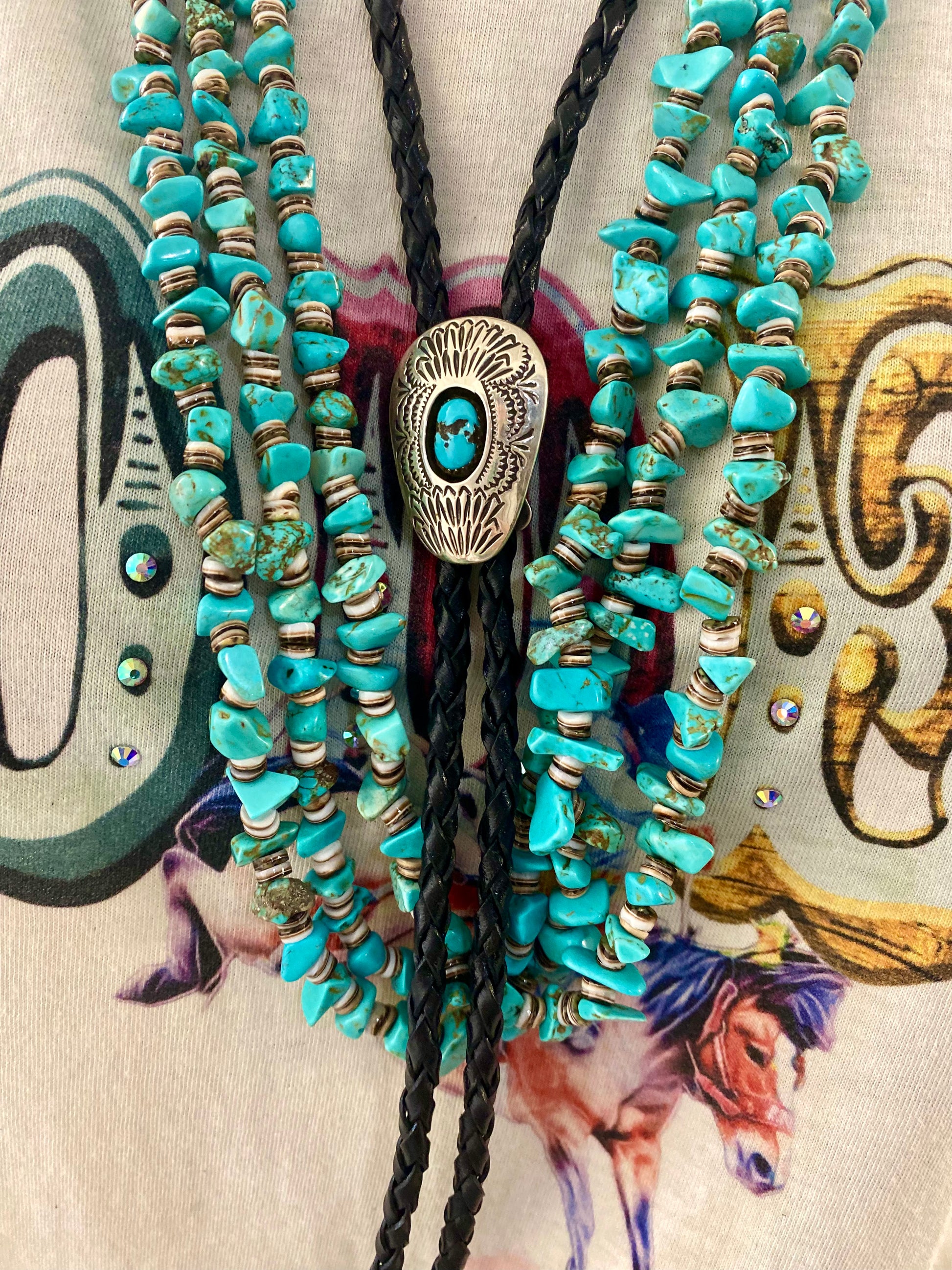 Black bolo tie necklace with single turquoise stone. A beautiful statement piece to add to your jewelry or formal attire collection. Bolo tie silver pendant with turquoise is adjustable. It can be slide up and down the leather bolo strands. The Angelo Turquoise Bolo Tie | Western Native Made Bolo 