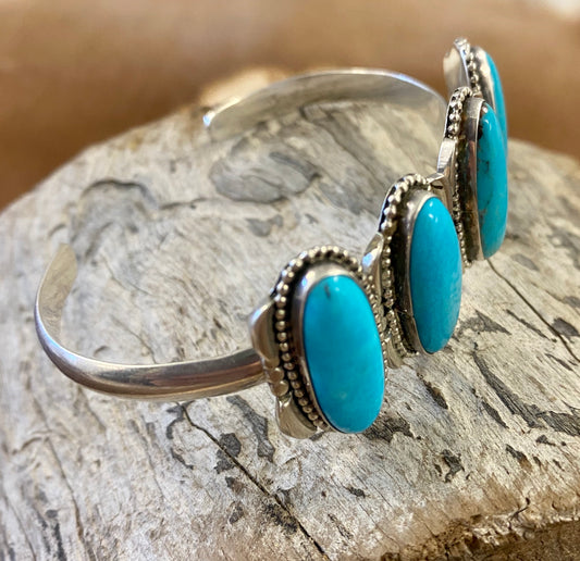 Silver four stone Native American made turquoise stamped sterling and signed cuff. This cuff is absolutely stunning and the perfect piece for your jewelry collection or give as a gift to a loved one. Stamped Sterling & Signed R.B. Inside of a bear icon for Running Bear Shop on the inside of the cuff.   Size:  Stones are 1” length 6.5” all the way around not including gap  Stone: Turquoise   Signed: YES "R.B." Inside of a bear icon   Hallmark/Artist: Running Bear Shop 