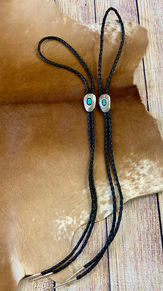 Black bolo tie necklace with single turquoise stone. A beautiful statement piece to add to your jewelry or formal attire collection. Bolo tie silver pendant with turquoise is adjustable. It can be slide up and down the leather bolo strands. The Angelo Turquoise Bolo Tie | Western Native Made Bolo