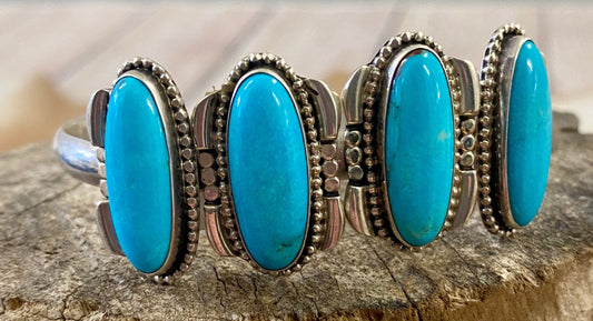 Silver four stone Native American made turquoise stamped sterling and signed cuff. This cuff is absolutely stunning and the perfect piece for your jewelry collection or give as a gift to a loved one. Stamped Sterling & Signed R.B. Inside of a bear icon for Running Bear Shop on the inside of the cuff.   Size:  Stones are 1” length 6.5” all the way around not including gap  Stone: Turquoise   Signed: YES "R.B." Inside of a bear icon   Hallmark/Artist: Running Bear Shop 